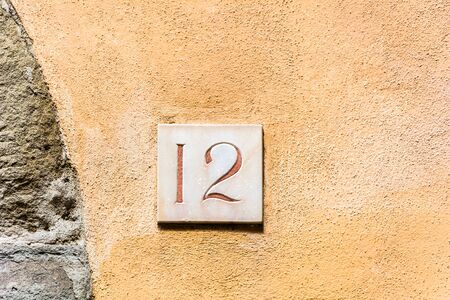 house number twelve ( 12 ) on a roughcast wall