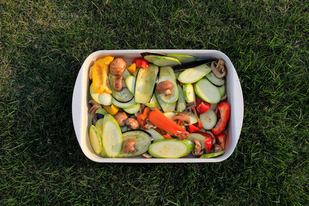 raw sliced   spring vegetarian vegetables in a pot on the green grassの写真素材