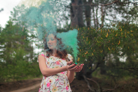 portrait of beautiful woman with cyan fog in her hands. Mist. Red hair, lips.の写真素材