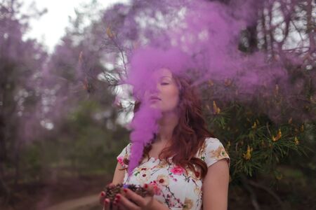 portrait of beautiful woman with purple fog, in ger hands.  mMst. Red hair, lips.の写真素材