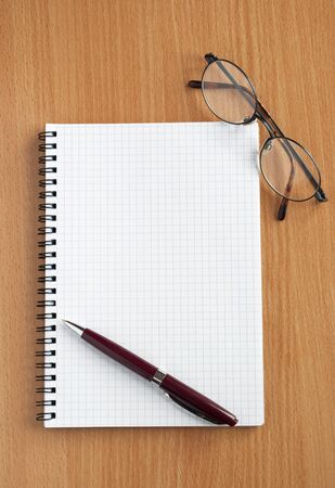 Notebook, glasses and pen on the table.の写真素材