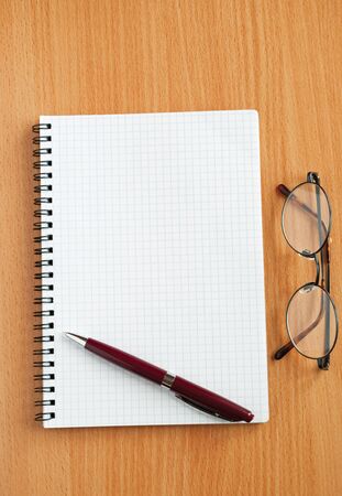 Notebook, glasses and pen on the table.の写真素材