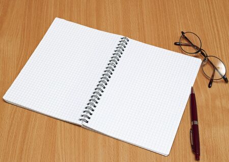 Notebook, glasses and pen on the table.の写真素材