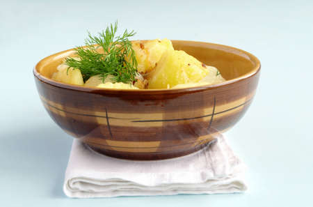 potatoes garnished with dill in a brown earthenware dishの写真素材
