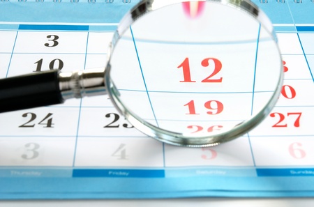 magnifying glass and a calendar to find the right timeの写真素材