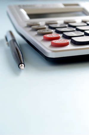 calculator and a pen on a blue backgroundの写真素材