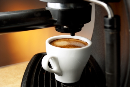 white cup filled with coffee in the coffee machineの写真素材
