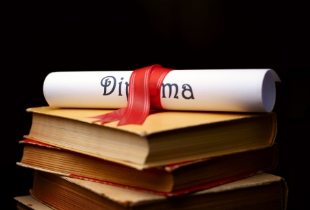 Diploma with red ribbon and a stack of booksの写真素材