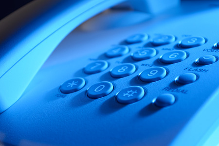 Keypad with numbers for dialling and function buttons on a landline telephone instrument in blue...
