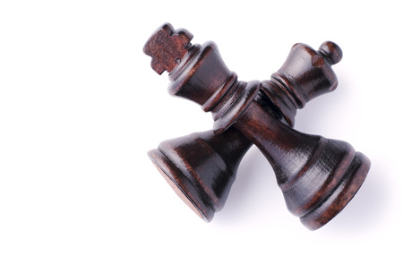 Overhead view of two crossed wooden king chess pieces lying on a white background, both in dark coloured woodの写真素材