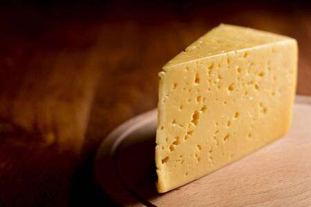 Close up of a delicious wedge of fresh cheese on a wooden cheese board with copyspace