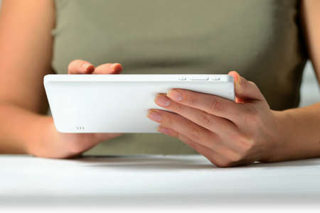 Hands of a man using a white slim PC tablet with high technology, close-up shot from low angle