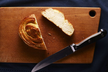 Overhead view of a cut bun with the slice lying alongside on a wooden breadboard with a sharp...