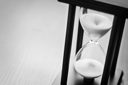 High angle close up view of sand running through an hour glass or egg timer measuring the passing time and counting down to a deadlineの写真素材