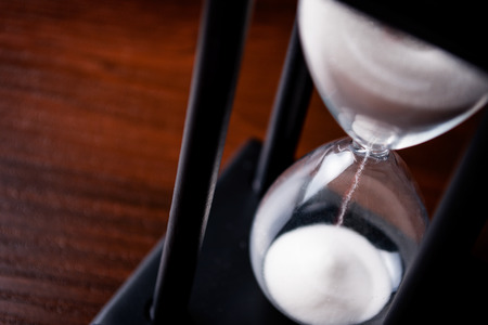 High angle close up view of sand running through an hour glass or egg timer measuring the passing time and counting down to a deadlineの写真素材