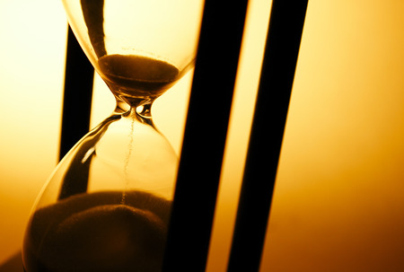 Conceptual image of measuring passing time with a close up view of sand running through an hourglass...