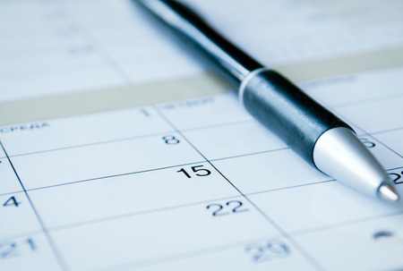 Ballpoint pen lying on a calendar with selective focus to the date of the 15th, calendar at an oblique angleの写真素材