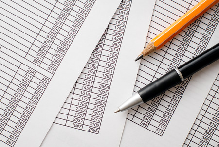 Business Concept - Close up Black Ballpoint Pen and Orange Pencil on Top of Business Documents with Number Prints.の写真素材