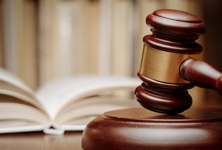 Wooden gavel resting on its end on a wooden table in front of an open law book conceptual of a judge, courtroom and judgementsの写真素材
