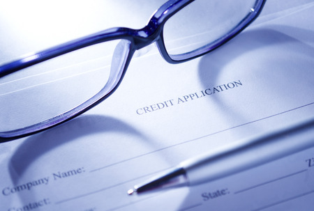 Conceptual Close up of Unisex Eyeglasses and Ballpoint Pen on Top of Blank Credit Application Form Paper.の写真素材