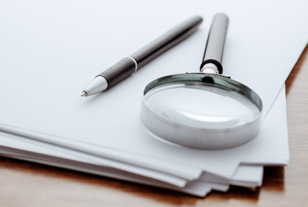 Magnifying glass, ballpoint pen close-up on white paper for notesの写真素材