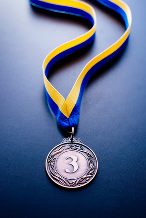 Bronze medal in the foreground on yellow blue ribbonの写真素材