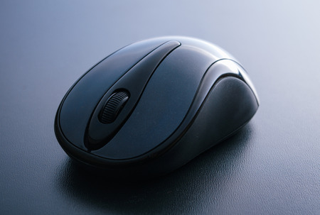 Wireless computer mouse on a blue leather rugの写真素材