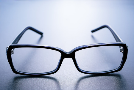 Horn-rimmed glasses with reflection on blue backgroundの写真素材