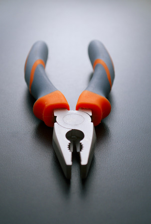 Close up One Combination Pliers Hand Tool with Orange and Gray Handles on a Gray Background.の写真素材