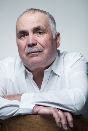 Close-up portrait of a Caucasian senior man with mustache wearing a white shirt while smiling at cameraの写真素材