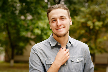 Portrait of a pensive young man with a beard, against a background of treesの写真素材