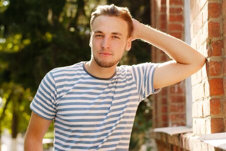 Portrait of a young man with a beard near a wall of the buildingの写真素材