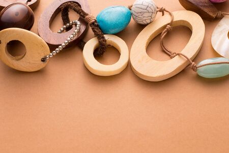 High Angle Close Up Still Life View of Handmade Artisan Jewellery on Tan Colored Background with Copy Space - Stylish and Modern Necklace with Wood Beads and Colorful Stones Secured with Leatherの写真素材