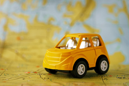 Yellow children's car before sending on a journey through the geographical mapの写真素材