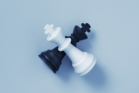 Two chess kings lying on a light blue background with slight set shadowの写真素材