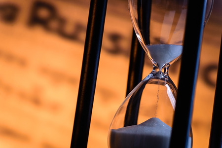 Sand running through an hourglass measuring passing time counting down towards a deadline, close up...