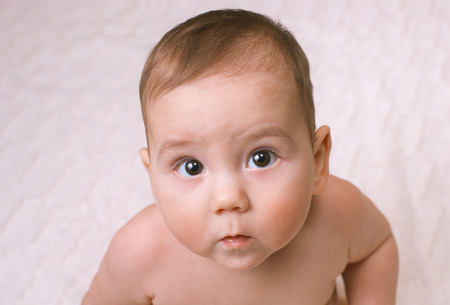 Curious little baby looking up at the camera with a look of deep concentration and wide eyes , close...