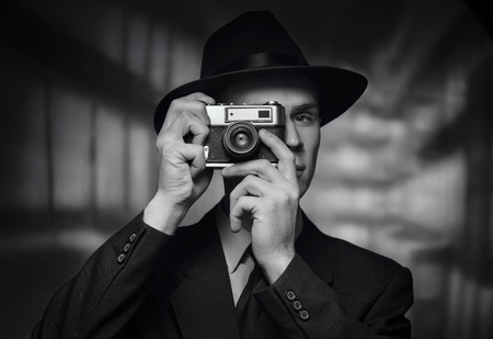Single 1950s man in business suit and hat taking a picture over urban building backgroundの写真素材