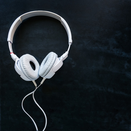 White headphones with cable on a black office deskの写真素材