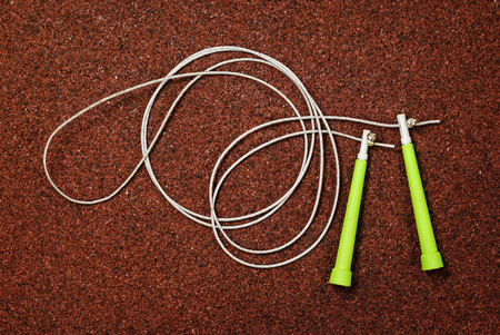 Green jump rope on a red background in the gym, for fitnessの写真素材