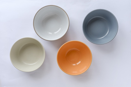 Assorted clean empty bowls and plates for food viewed from above as a full frame background on whiteの写真素材