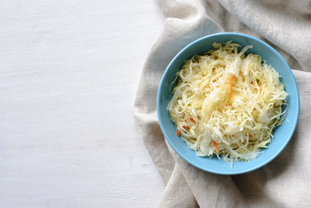Blue bowl with sauerkraut on a white table, healthy foodの写真素材