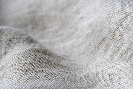 Texture if natural linen fabric draped in waves in a full frame background with shallow dof and copy spaceの写真素材