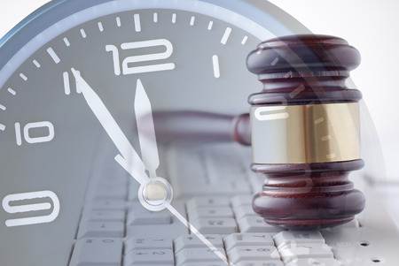 Law enforcement or auction concept with wood and brass gavel upright on a white computer keyboard...