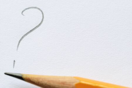 Sharp pencil lying next to question mark on white paper with copy space.の写真素材