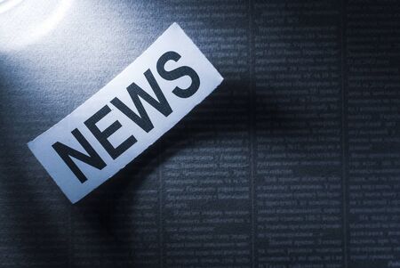 Closeup of news inscription on white sheet on background of black newspaper