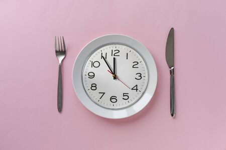 Pink table setting with a clock on a plate showing five minutes to twelve ready for the lunch break...