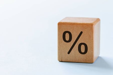 One wooden dice with percent symbol printed on its one side, viewed in close-up with shadow on white background and with copy spaceの写真素材