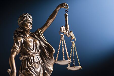 Bronze figurine of a blindfolded Lady Justice with her scales representing law and order on a blue...