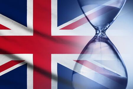 Hourglass with sand running through measuring passing time to a deadline with the British Union Jack flag in a conceptual imageの写真素材